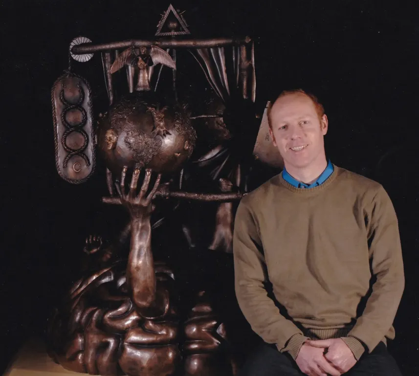 man sitting next to sculpture